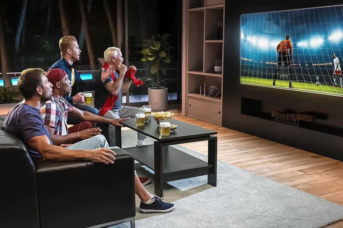 Des amis célèbrent en regardant un match de soccer sur un grand téléviseur