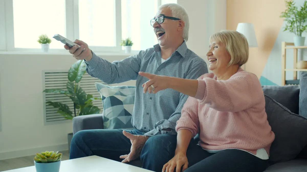 Des grands-parents regardent la télé ensemble à la maison